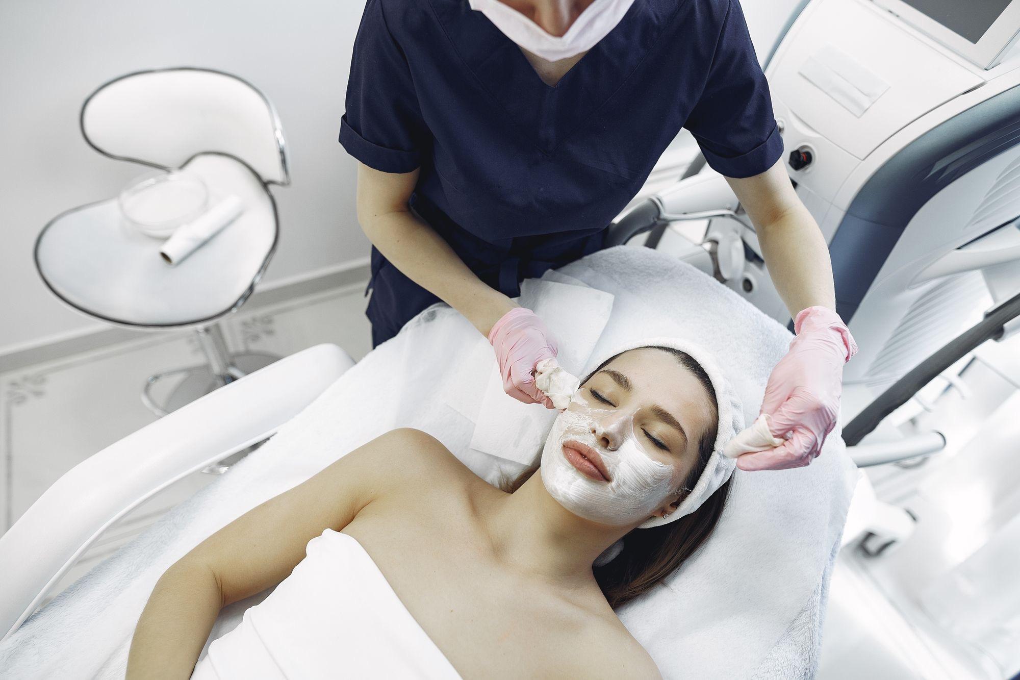 Aesthetician finishing a facial treatment in a clinical treatment room