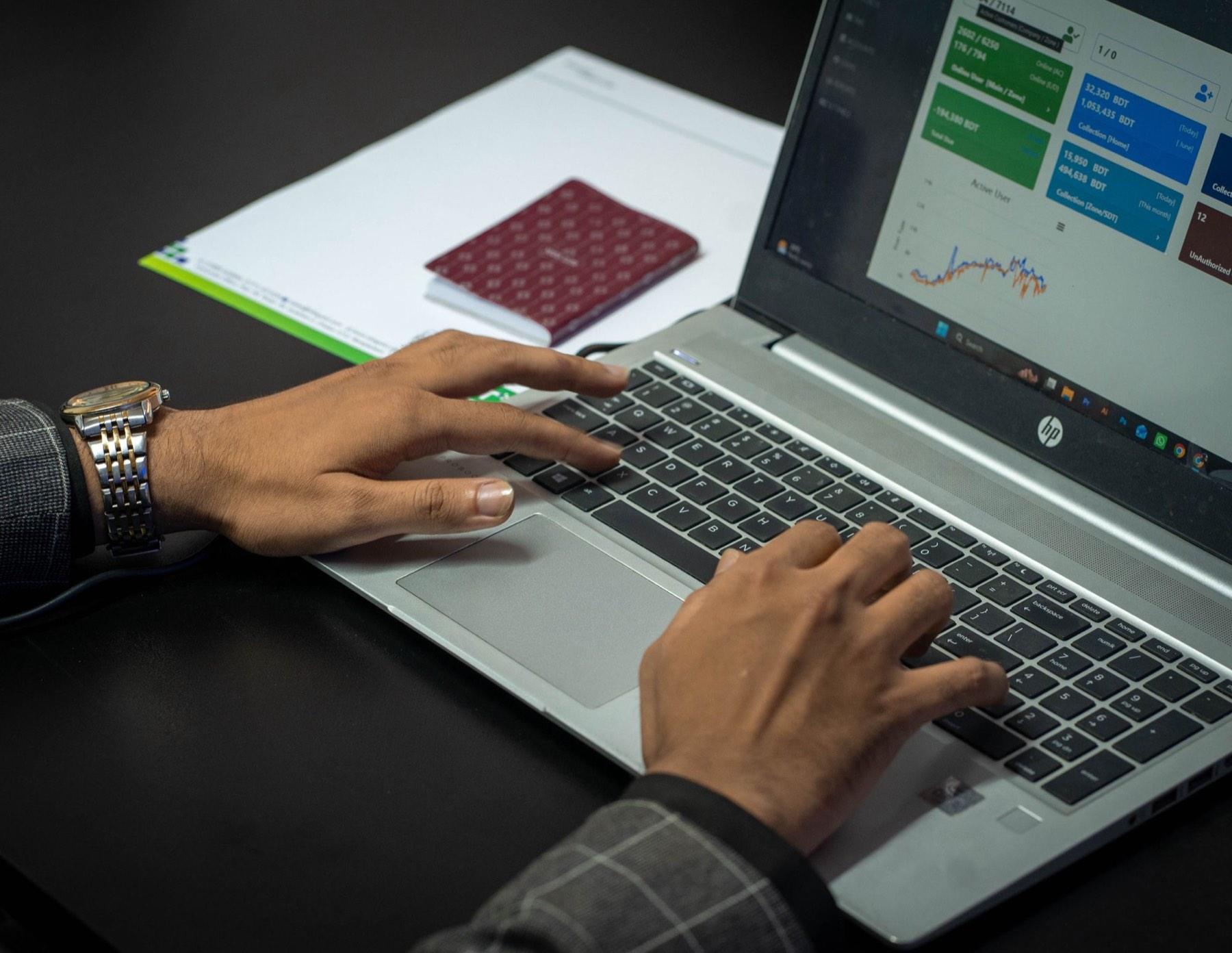 Hands on a laptop keyboard with an analytics dashboard on screen