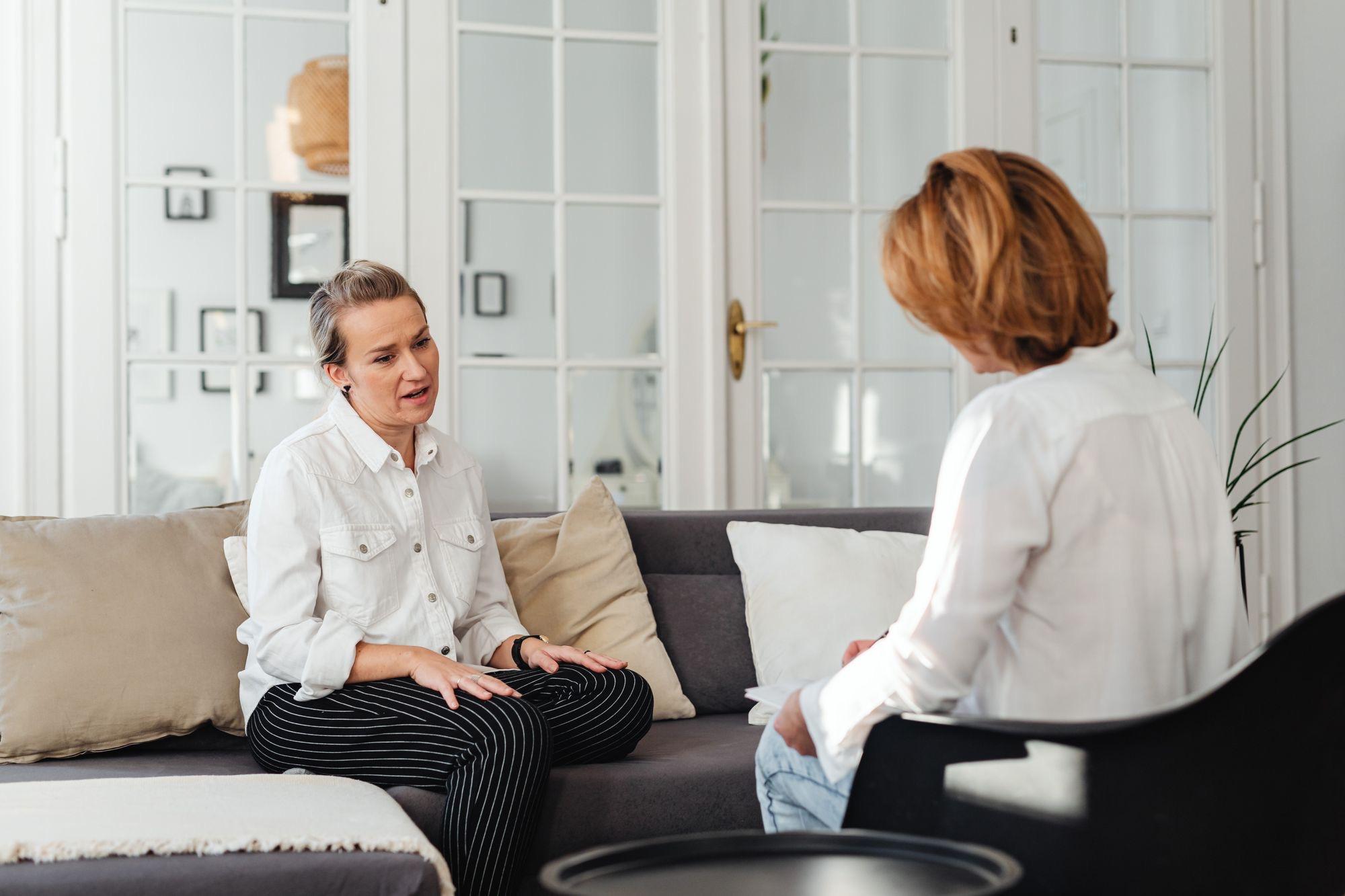 Two people in a quiet counseling conversation in a bright room