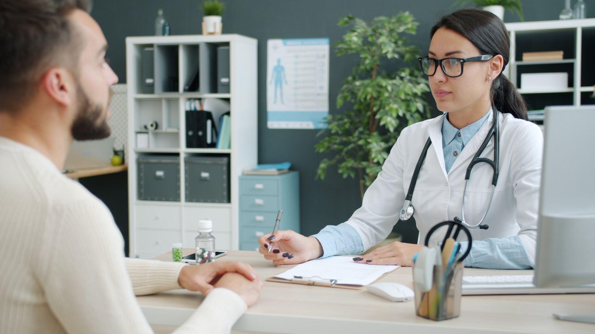 Clinician taking notes during a consult with a male patient