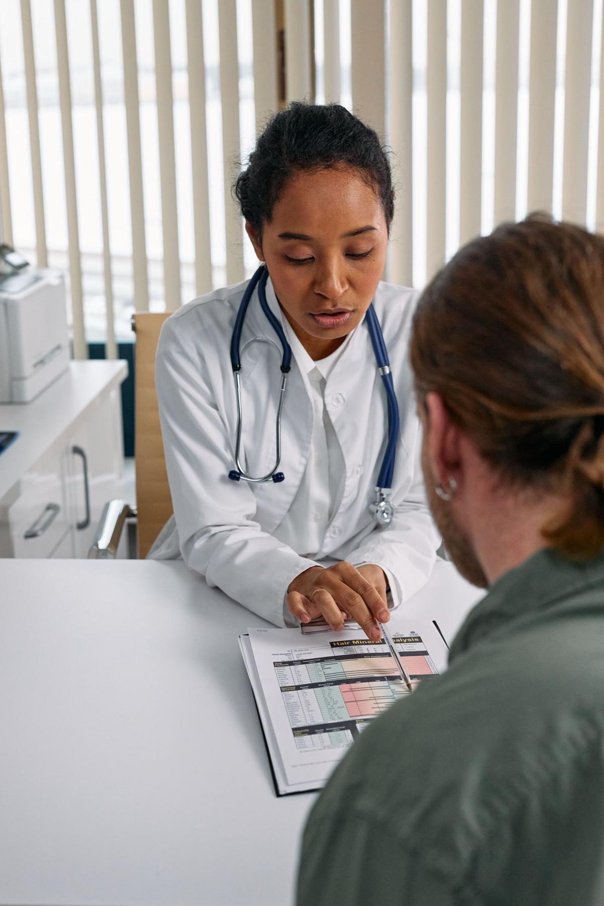 Clinician walking a patient through lab results on a clipboard